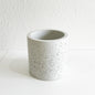 Concrete planter with speckled texture on a white surface and background