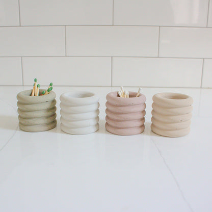 four assorted colored jars holding matches