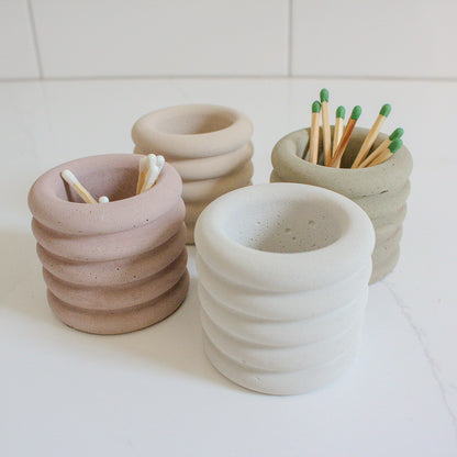 four assorted colored jars holding matches